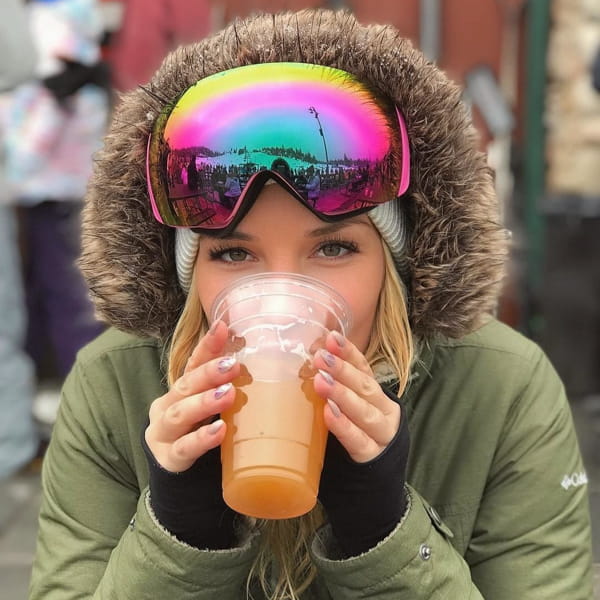 female drinking a beer wearing snow gear
